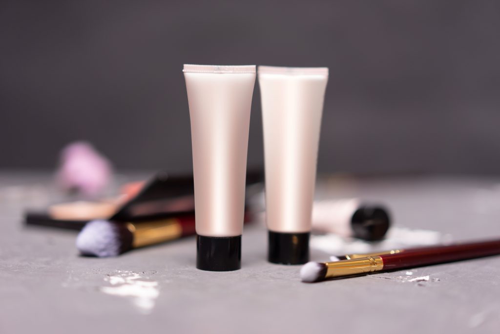 Pourquoi nous choisir Close-up of skincare tubes with makeup brushes on a table, symbolizing beauty and self-care.
