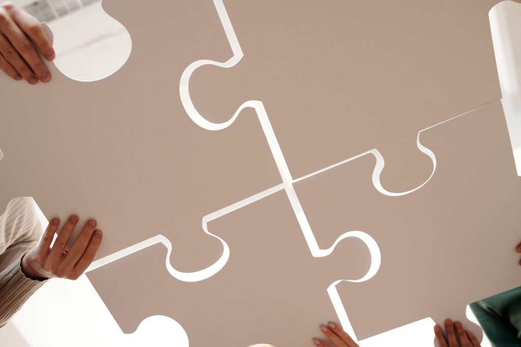 Pourquoi nous choisir Hands of diverse individuals holding large puzzle pieces, symbolizing teamwork and unity.